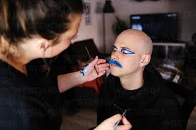 female artist doing makeup of bald man