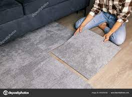 woman laying self adhesive carpet tiles