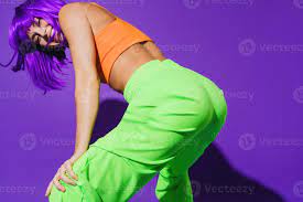 Carefree woman wearing colorful sportswear twerking against purple  background 16256113 Stock Photo at Vecteezy