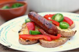 a plate of grilled smoked sausage and potatoes topped with grilled red pepper strips jalapeno