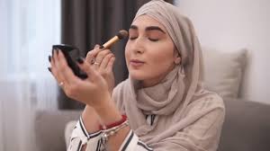 muslim woman doing makeup on her face
