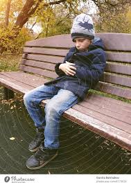 sad boy sitting on bench alone outdoor