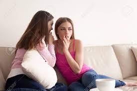 Two Close Girlfriends Sharing Scandalous News. Young Attractive Woman  Telling Incredible Secret To Her Friends Ear While Sitting On Sofa In  Living Room. Surprised Lady Listening Interesting Gossips Stock Photo,  Picture and