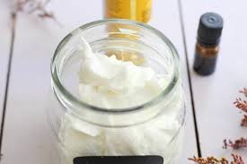 a gl jar filled with whipped coconut oil on a table with essential oils and herbs