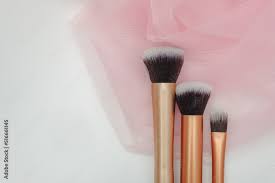 several makeup brushes on a light pink