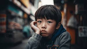 sad asian boy sitting in a crowded city