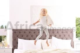 cute little girl with pillow jumping on