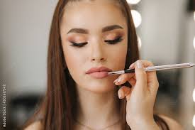 makeup artist applies lipstick hand of
