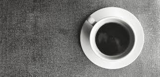 white cup of black coffee on brown rug