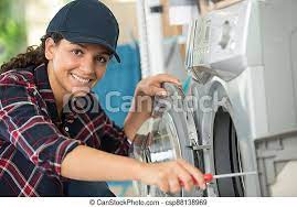 Young woman repairing a washing machine. | CanStock