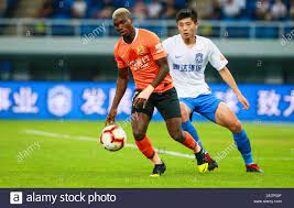 Ivorian football player Jean Evrard Kouassi, left, of Wuhan Zall passes the  ball against a player of Tianjin TEDA in their 23rd round match during the  Stock Photo - Alamy