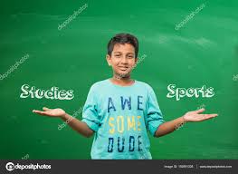 Indian School Kid Or Boy Standing In Front Of Green Chalkboard With