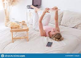 一位纤瘦的女子，早晨躺在白床上，手里拿着一个数字平板电脑库存图片- 图片包括有全能, 电话: 257493097