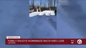 family enjoys homemade backyard sled luge