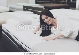 Hybrid mattresses offer the benefits of both a memory foam and innerspring combined into one base upgrade: A Woman Chooses A Mattress In A Store She Decided To Lie Down And Try It A Woman In A White Shirt And Jeans In A Mattress Canstock