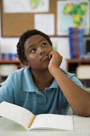 Elementary School Student Leaning On Elbow Daydreaming In Class
