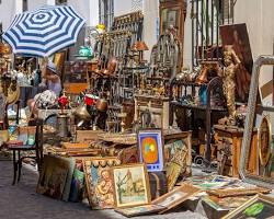Personas comprando y vendiendo antigüedades en un mercado en una calle de Madrid puesto donde hay todo tipo de objetos de distintas epocas en venta
