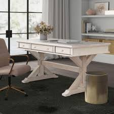 The wooden desktop has a natural finish, and sits atop a brass base with four slim, slightly splayed legs. Rustic Desks Joss Main