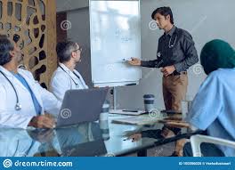 Male Doctor Explaining Over Flip Chart In Meeting At