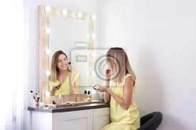 woman applying makeup near mirror with