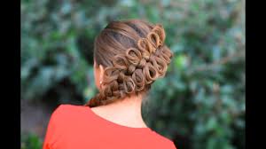 Dutch braids are coiled into side buns and decorated with thin golden ribbon in this example. How To Create A Diagonal Bow Braid Youtube