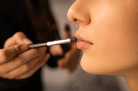 makeup artist applies lipstick