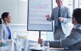 Businessman Leading Meeting At Whiteboard Flip Chart In Conference Room D985_37_153