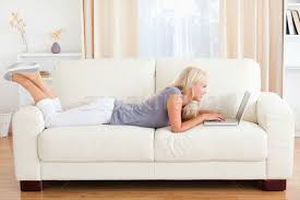 Woman Lying On A Sofa Using A Laptop In