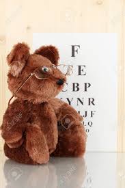 Teddy Bear With Glasses On Eyesight Test Chart Background Close Up
