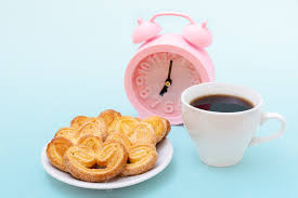 Taza blanca de humeante café negro o chocolate caliente, galletas en forma  de corazón recién horneadas y reloj despertador rosa sobre fondo azul  claro, | Foto Premium
