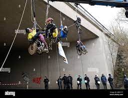 Titz, Germany. 16th Jan, 2023. A police height rescuer helps an  environmental activist in a wheelchair to the ground. Climate activists in  wheelchairs rappelled down from a highway bridge on the A44