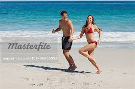 funny couple running on the beach with
