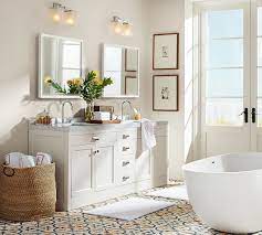 Sophisticated bathroom features a black vanity topped with white quartz placed under a nailhead mirror, pottery barn farrah nailhead mirror, illuminated. Classic Glass Bathroom Canisters Small Bathroom Makeover Bathroom Wall Decor Bathroom Makeover
