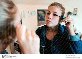 young woman applying makeup to eyes in