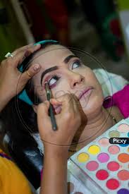 an indian woman getting eye makeup at
