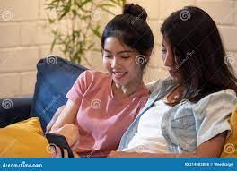 Happy Asian Lesbain Couple Watching Video on Mobile Phone Together on Sofa  in Night Time at Home with Chill Out Emotion.woman Stock Photo - Image of  online, embrace: 214803858