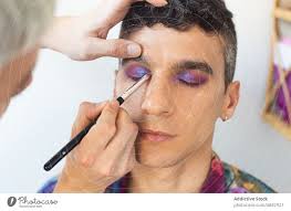 androgynous man getting makeup done by