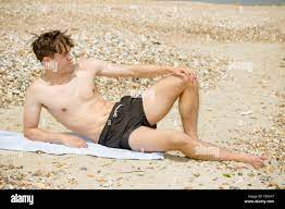 Young adult caucasian male sunbathing on a beach Stock Photo - Alamy