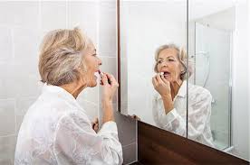 60 year old lady applying makeup stock