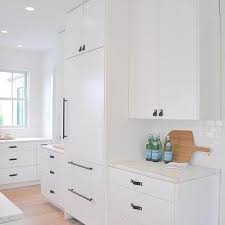 White shaker cabinets with white countertops and white ceramic tile backsplash. White Kitchen Cabinets With Matte Black Hardware Liberalx