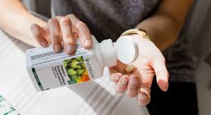 a woman s hand is shown pouring a nutrilite vitamin c tablet from the bottle into the