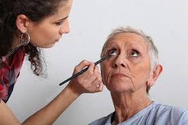 woman applying makeup to an older lady