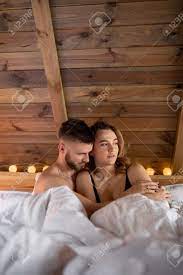 一緒にいる幸せ。若い男はベッドに座っている間、彼の最愛の人を優しく抱きしめます。感情が大好きです。安全なセックス。ロマンチックなデート。自由な関係。家族生活。天然素材。の写真素材・画像素材  Image 187134433