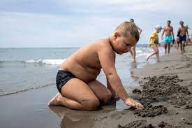 boy with blond hair on a sandy beach