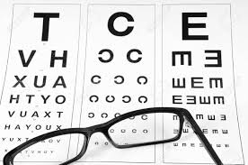 Reading Eyeglasses And Eye Chart Close Up On A Light Gray Background