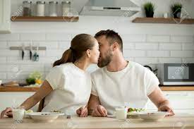 Loving Sensual Couple Enjoying Homemade Cooked Meal Kissing Sitting At  Dining Table In The Kitchen, Affectionate Young Man And Woman Having Dinner  Together On Pleasant Good Morning Breakfast At Home Stock Photo,