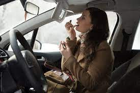 woman doing makeup car by stocksy