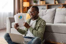 Happy Busy Middle Aged Black Male In Glasses Shows Graphs, Charts In Webcam  Computer Sits On Floor Stock Photo, Picture And Royalty Free Image. Image  195606253.