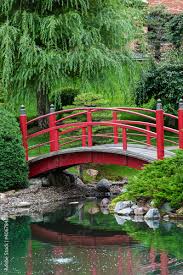 Lush Green Park Red Bridge Over A Pond