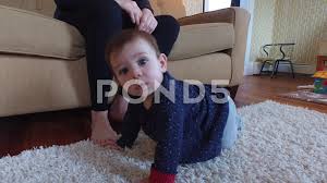 a baby crawling at her mother s feet on